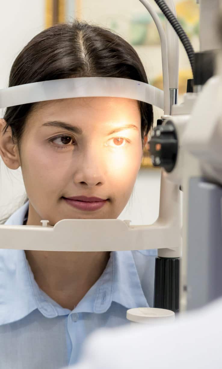 Woman having her left eye tested by an ophthalmologist device to determine eye health