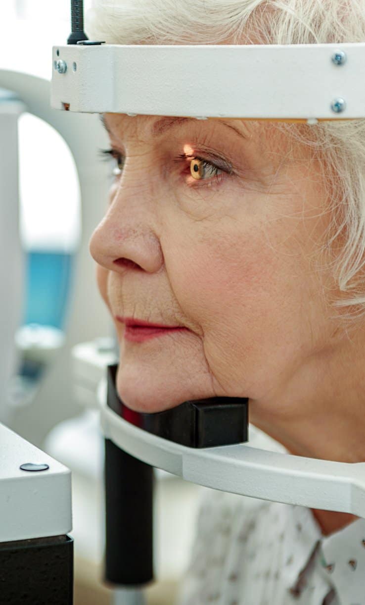 A woman having her left eye examined by an ophthalmologist for eye health relating to retinal detachment